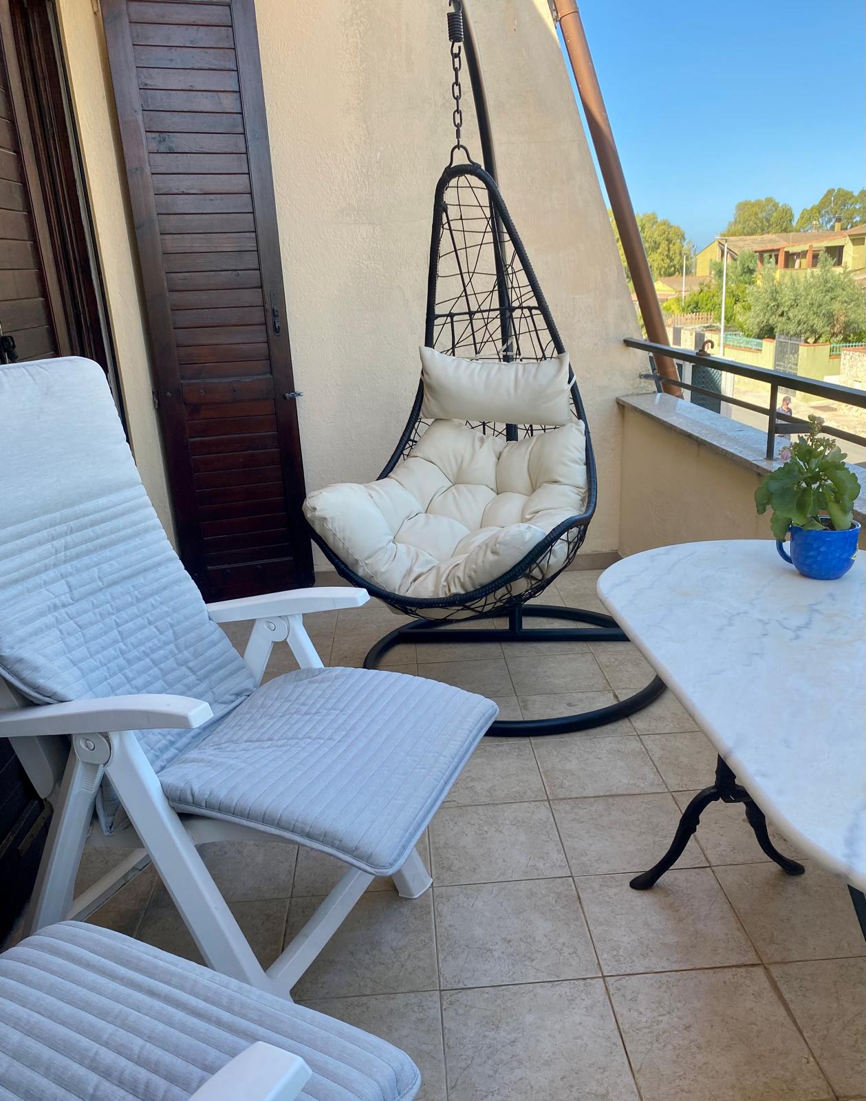 Balcone di Casa JIL con poltrona sospesa, sedute e tavolo